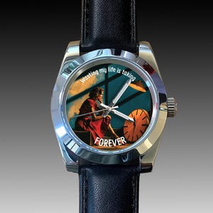 May include: A silver wristwatch with a black leather strap. The watch face displays an image of a person in a red dress and the words "Wasting my life is taking FOREVER."