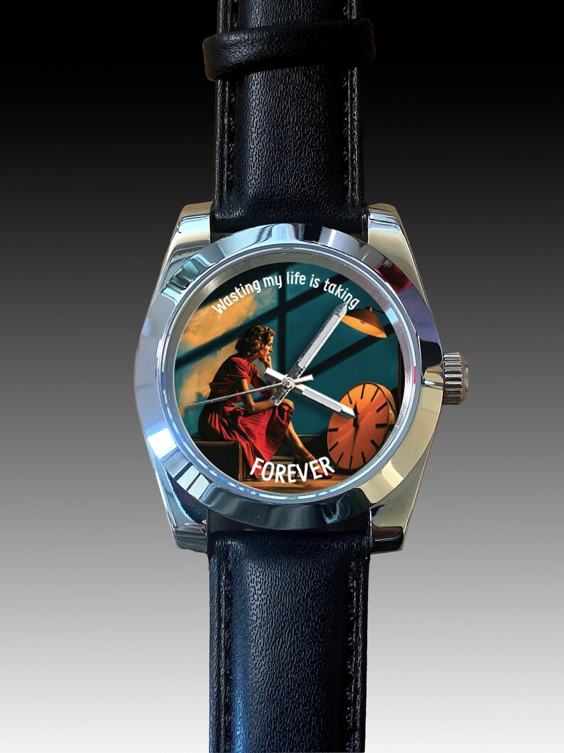 May include: A silver wristwatch with a black leather strap. The watch face displays an image of a person in a red dress and the words "Wasting my life is taking FOREVER."
