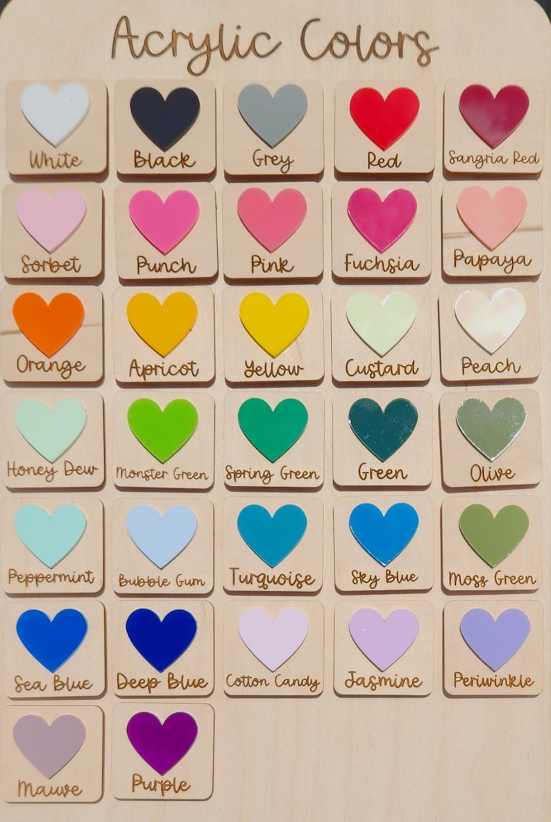 May include: Wooden color chart with acrylic heart-shaped color samples. The chart includes a variety of colors, such as red, pink, green, blue, and purple, with each color labeled with its name. The text "Acrylic Colors" is at the top.