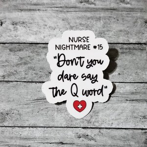 Pu&ograve; includere: Adesivo bianco con testo nero che dice "NURSE NIGHTMARE #15 "Don't you dare say the Q word" con un cuore rosso e un segno pi&ugrave; al centro.