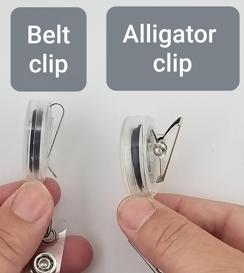 May include: Two clear plastic badge reels are shown, one with a belt clip and the other with an alligator clip. The text "Belt clip" and "Alligator clip" are displayed above each reel. The reels are held by hands.