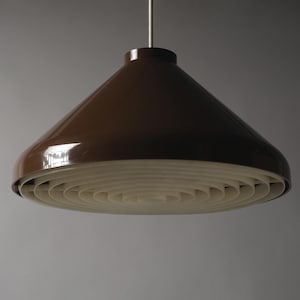 May include: A brown, cone-shaped pendant light fitting with a glossy finish. The light has a white, layered, circular diffuser at the bottom. The fitting hangs from a thin, silver-coloured wire.