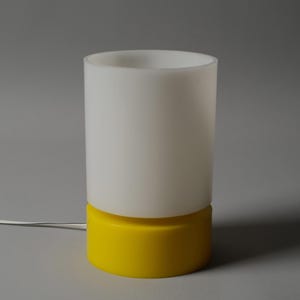 Vintage 1970s Harvey Guzzini table lamp with yellow cylindrical base and opaline diffuser.