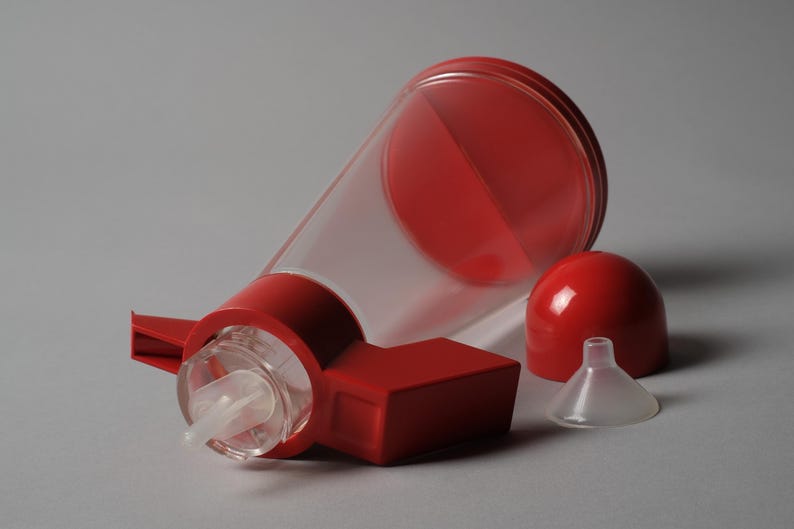 The Interaction Point. This sixth and final image provides a dynamic close-up of the Bicondi's red top assembly, showcasing the pivot mechanism that gives the object its name and unique utility.