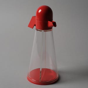 Postmodern Clarity. This second image provides a direct front view of the Bicondi cruet, highlighting the sharp contrast between the clear conical reservoir and the vibrant red geometric top. The design language is unmistakably 1980s Italian, prioritizing bold shapes and vibrant color palettes while remaining a high-performance kitchen tool.