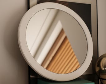 Vintage 1970s round wall mirror with white plastic frame.