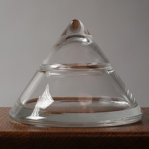 The Pyramidal Form. This first image introduces a striking 1980s crystal glass bonbonnière. This piece is a quintessential example of Postmodern minimalism, stripping away all surface ornamentation to focus entirely on the interplay of light and pure geometric volume. The two-part construction creates a perfect conical silhouette that feels both ancient and futuristic.