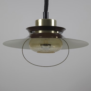 May include: A retro pendant light fitting with a brown and gold finish. The light features a round, frosted glass shade and a black cord. The design of the fitting is reminiscent of mid-century modern styles.