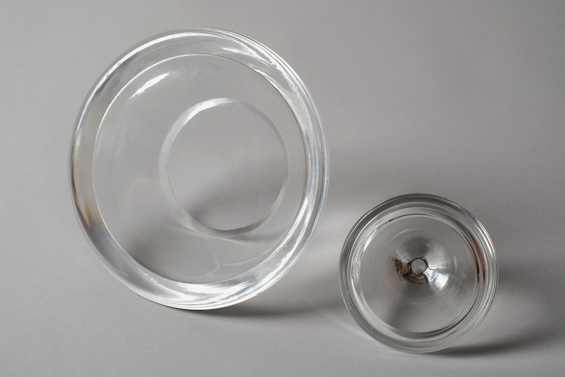 The Underside Foundation. This seventh and final image reveals the base of both components from a high angle. The underside of the vessel is characterized by a wide, flat, polished ring that provides maximum surface contact, ensuring the heavy crystal pyramid remains stable on any flat surface. This perspective also highlights the annular geometry of the piece, with concentric circles formed by the varying thicknesses of the crystal walls.