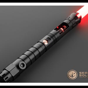 May include: A black lightsaber with a red blade. The lightsaber has a textured grip and a silver button on the side. The blade is lit and extends from the hilt.
