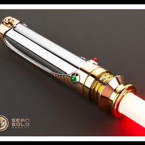 May include: A metallic lightsaber with a silver body and gold accents. The hilt features a red and green button, and the blade emits a bright red glow. The Sean Solo Sabers logo is visible in the lower left corner.