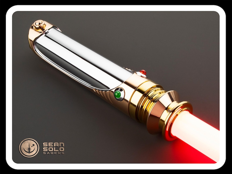 May include: A metallic lightsaber with a silver body and gold accents. The hilt features a red and green button, and the blade emits a bright red glow. The Sean Solo Sabers logo is visible in the lower left corner.