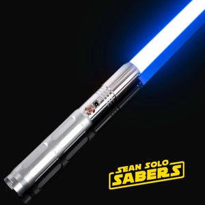 Pu&ograve; includere: Una spada laser argentata con una lama blu. La spada laser ha un pulsante nero e un'impugnatura testurizzata. La lama &egrave; accesa e si estende dall'impugnatura. La spada laser &egrave; su uno sfondo nero. Il testo "SEAN SOLO SABERS" &egrave; in lettere gialle su uno sfondo nero.