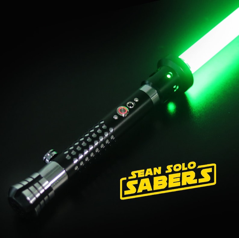 May include: A black and silver lightsaber with a green blade. The lightsaber has a textured grip and a red button. The text "SEAN SOLO SABERS" is visible in the lower right corner of the image.