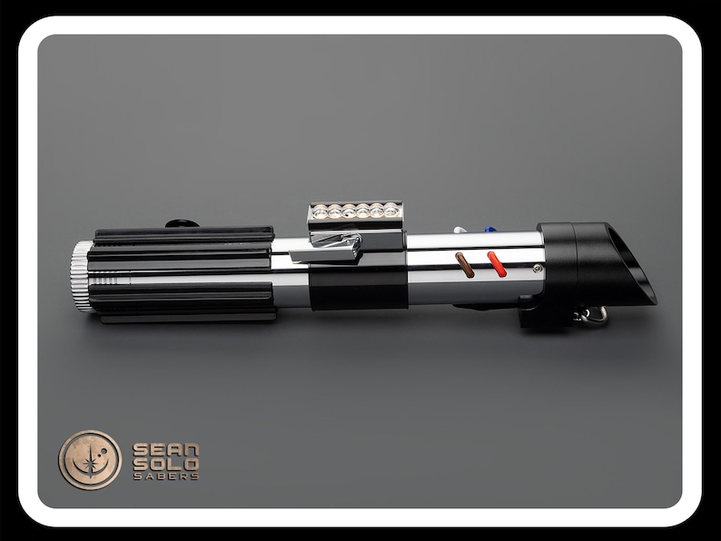 Op de afbeelding: Een zwart en zilveren lightsaber met een rode en bruine accent. De lightsaber heeft een reeks kleine lampjes aan de bovenkant.