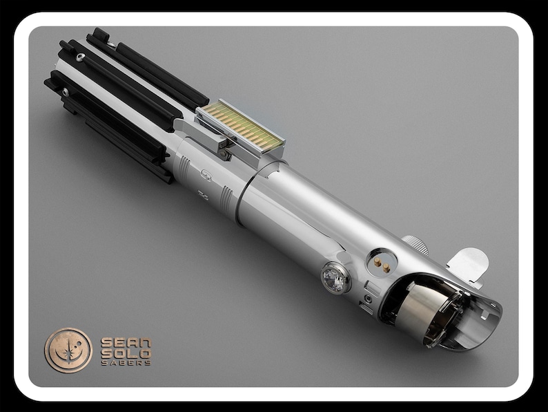 Puede incluir: Un detallado sable de luz plateado con detalles en negro y dorado. El accesorio presenta un dise&ntilde;o complejo con varios botones, interruptores y un emisor transparente. El logotipo de Sean Solo Sabers es visible en la esquina inferior izquierda.