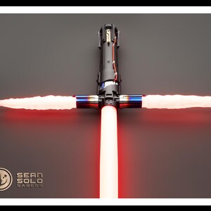 May include: A red lightsaber with a black hilt and a crossguard. The lightsaber is lit and the blades are extended. The lightsaber is on a gray background. The text "SEAN SOLO SABERS" is visible in the lower left corner of the image.