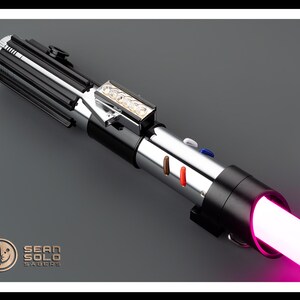 Op de afbeelding: Een zwart en zilveren lightsaber met een roze blade. De lightsaber heeft een zilveren handvat met een zwarte grip en een zwarte emitter. De blade is verlicht en straalt een roze gloed uit.