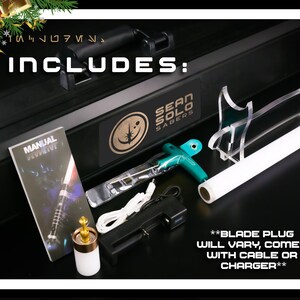 Op de afbeelding: Een zwarte koffer met de woorden "INCLUDES" en "SEAN SOLO SABERS" erop gedrukt. De koffer bevat een handleiding, een lightsaber-blad, een oplaadkabel, een voedingsadapter en een lightsaber-bladplug. De tekst "BLADE PLUG WILL VARY, COMES WITH CABLE OR CHARGER" is op de koffer gedrukt.