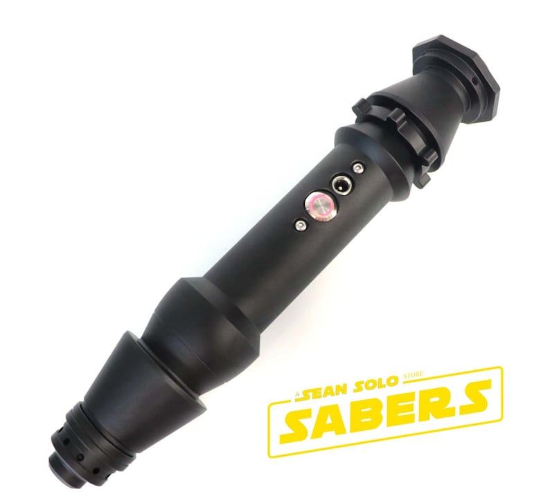 Może przedstawiać: Czarna rękojeść miecza świetlnego z czerwonym przyciskiem i kablem zasilającym. Rękojeść ma fakturowaną powierzchnię i srebrny pierścień wok&oacute;ł środka. Rękojeść jest oznaczona "Sean Solo Sabers Store".