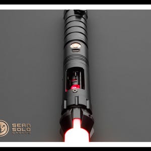 May include: A black lightsaber with a red blade. The lightsaber has a silver button and a black handle with a silver band.