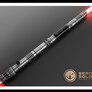 May include: A double-bladed lightsaber with a metallic silver and black hilt featuring intricate cutouts, ribbed sections, and two black activation switches. The blade emits a bright red glow from both ends. The Sean Solo Sabers logo is visible.