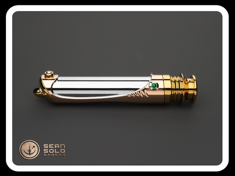 May include: A metallic lightsaber with gold, silver, and copper accents. The hilt features a green gem and intricate detailing. The product is displayed on a dark gray background with the "Sean Solo Sabers" logo.