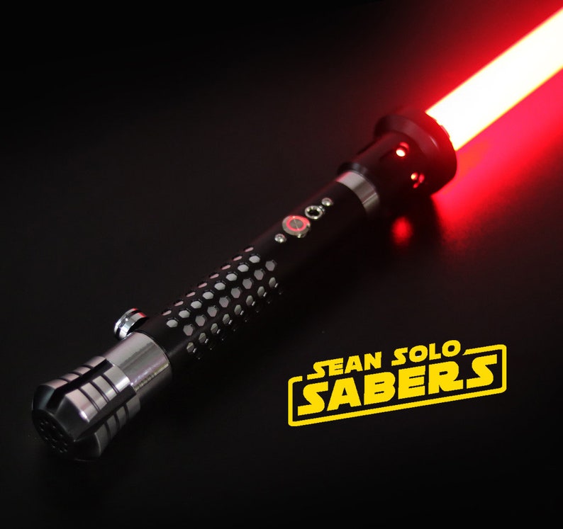May include: A black lightsaber with a red blade and a silver handle. The lightsaber has a textured grip and a small button on the side. The lightsaber is lit up and the blade is glowing red. The lightsaber is on a black surface. The text "SEAN SOLO SABERS" is in yellow letters on the surface.