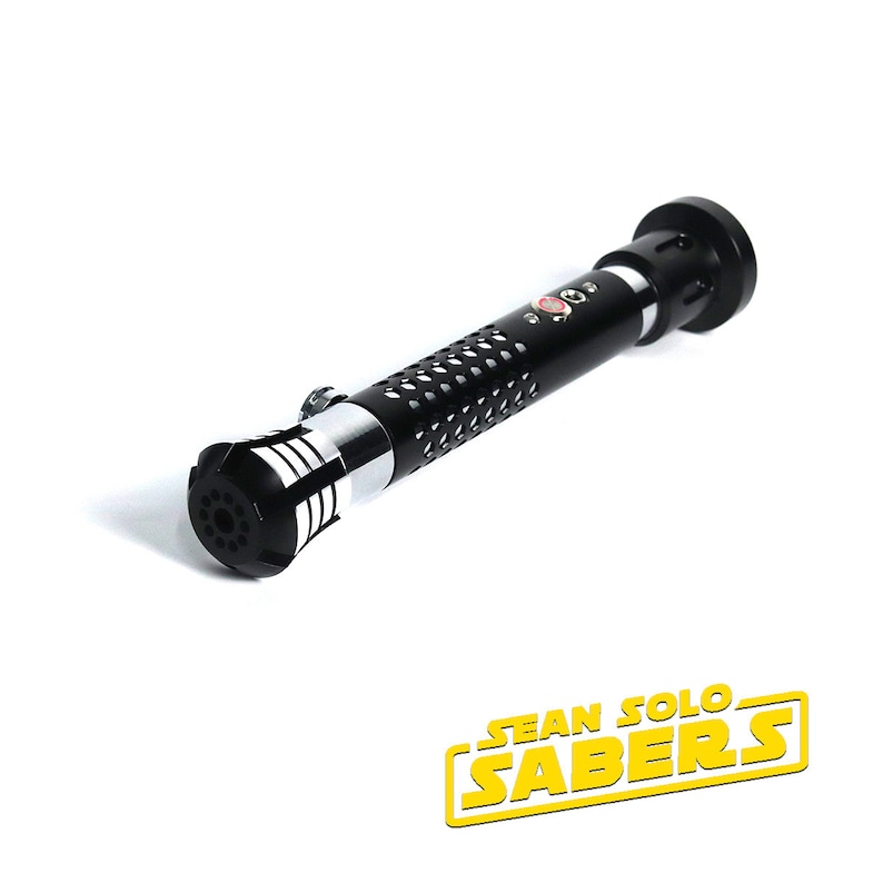 May include: A black lightsaber hilt with a silver accent and a red button. The hilt has a textured surface and a round end. The hilt is labeled "SEAN SOLO SABERS".