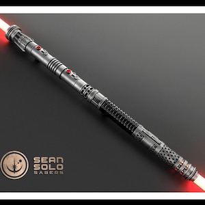 May include: A double-bladed lightsaber with a metallic silver and black hilt featuring red button accents and glowing red blades at both ends. The hilt has a textured grip and intricate mechanical detailing. A logo reads SEAN SOLO SABERS.
