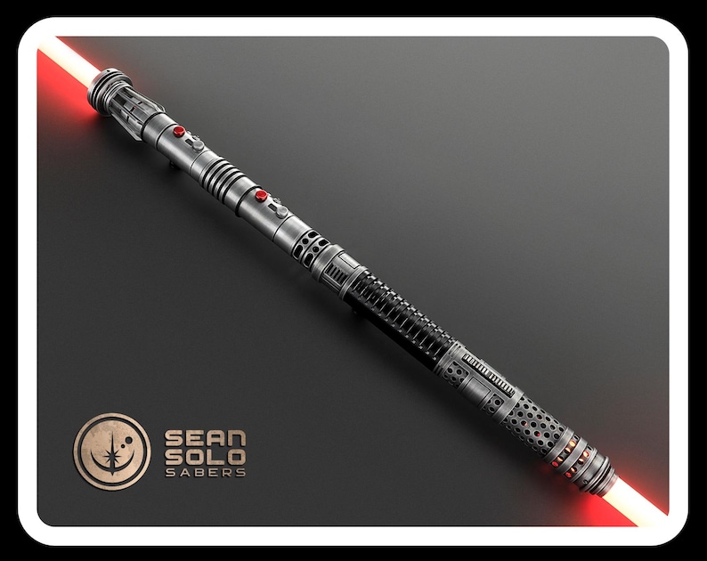 May include: A double-bladed lightsaber with a metallic silver and black hilt featuring red button accents and glowing red blades at both ends. The hilt has a textured grip and intricate mechanical detailing. A logo reads SEAN SOLO SABERS.