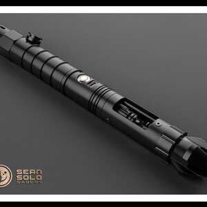 May include: A black lightsaber with a silver button and a partially exposed internal mechanism. The lightsaber is made by Sean Solo Sabers.