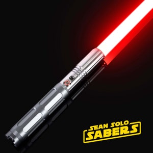 Pu&ograve; includere: Una spada laser argentata con una lama rossa. La spada laser ha un pulsante nero e un'impugnatura argentata con una presa testurizzata. La lama &egrave; accesa e si estende dall'impugnatura. La spada laser &egrave; su uno sfondo nero. Il testo "SEAN SOLO SABERS" &egrave; in lettere gialle su uno sfondo nero.