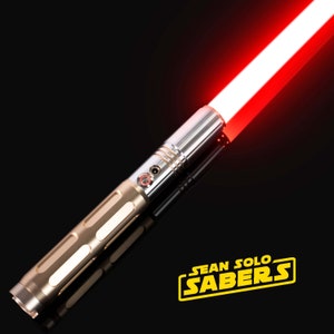 Pu&ograve; includere: Una spada laser dorata e argentata con una lama rossa. La spada laser &egrave; accesa e la lama &egrave; illuminata. La spada laser &egrave; etichettata "SEAN SOLO SABERS".