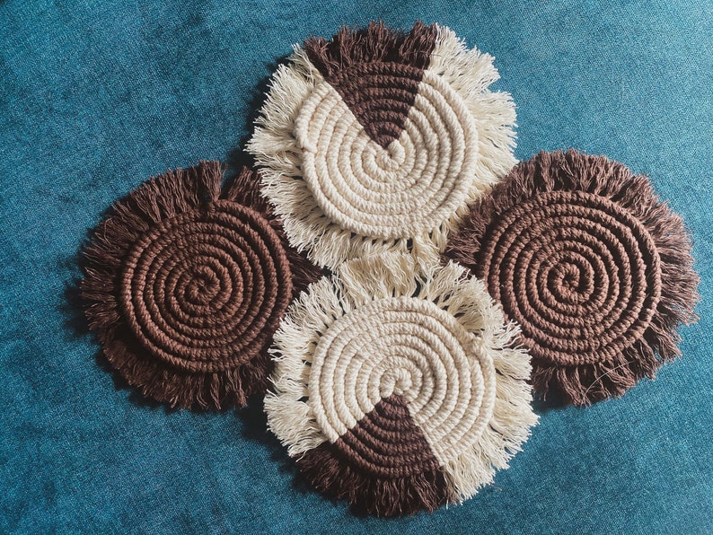 Pode incluir: Quatro  costas de croch&ecirc; feitos &agrave; m&atilde;o com um esquema de cores marrom e branco. Os  costas t&ecirc;m uma borda de franja e s&atilde;o feitos com um padr&atilde;o em espiral.