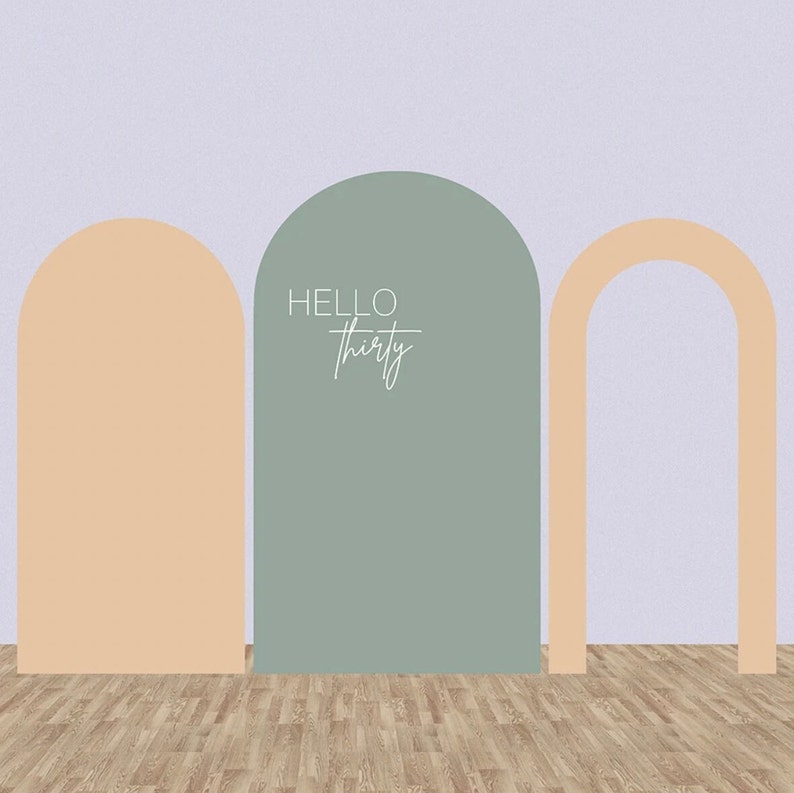 May include: A light green arch with the text "HELLO thirty" in white.  Two peach-colored arches flank the green arch.  The arches are in front of a light purple wall and a wood floor.