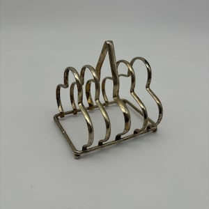 May include: Silver-plated toast rack with a simple design. The rack has five slots for holding toast.