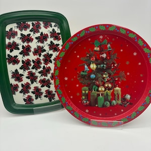 May include: Two metal serving trays with Christmas designs. One tray is green with a white holly pattern. The other tray is red with a Christmas tree and candles.