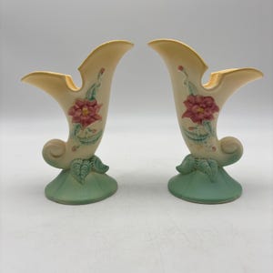 May include: Pair of vintage ceramic vases in a horn shape. The vases are cream-colored with a red flower and green leaves design. The base is a light green color. The vases are approximately 8 inches tall.