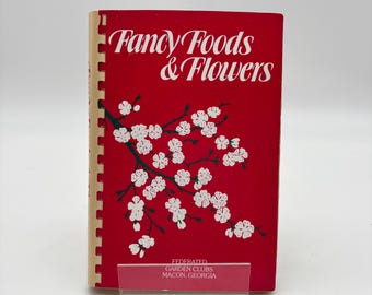 May include: A red spiral-bound book titled Fancy Foods & Flowers with a white cherry blossom branch illustration on the cover. The text Federated Garden Clubs Macon, Georgia is printed in white at the bottom of the front cover.