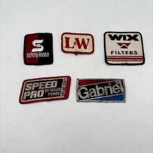 May include: A collection of five rectangular embroidered patches featuring automotive brand logos. The patches include Safety-Kleen, L&W, Wix Filters, Speed Pro by Sealed Power, and Gabriel, displayed in red, white, black, and blue color schemes.