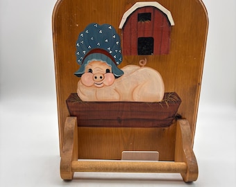 Vintage wooden country-style wall-mounted hand towel holder. Hand painted pig in a bonnet next to a small red barn