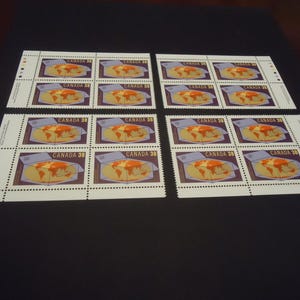 Könnte beinhalten: Ein Bogen mit sechzehn Briefmarken, die eine Grafik eines Globus in einer Schachtel zeigen, mit dem Text CANADA 38 auf jeder Marke. Die Briefmarken sind in zwei Blöcken zu je acht angeordnet, jeweils mit weißem Rand und perforierten Kanten.