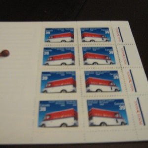 Op de afbeelding: Een vel Canadese postzegels met een rood-witte postwagen tegen een blauwe lucht. Elke postzegel is gemarkeerd met "Canada 39". Links van de postzegels bevindt zich een klein houten voorwerp.