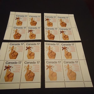 Op de afbeelding: Vellen Canada 17 postzegels. Elke postzegel toont een hand met een bruine strik om de wijsvinger. De tekst "Canada 17" en "Postal Code" staan op elke postzegel. De postzegels staan op een witte achtergrond.