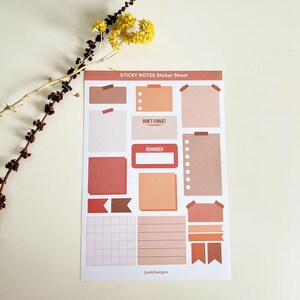 Op de afbeelding: Een vel met sticky notes in verschillende vormen en maten. De notities zijn in tinten bruin, oranje en rood. Het vel bevat een gegridde notitie, een gelinieerde notitie en verschillende lege notities. De tekst "STICKY NOTES Sticker Sheet" staat bovenaan het vel. De tekst "JuulsDesigns" staat onderaan het vel.