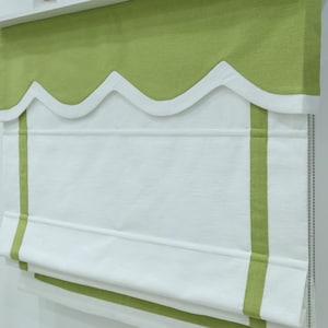 May include: White roman shade with green trim and scalloped valance. The shade has two green stripes along the bottom.