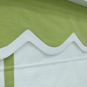 May include: A green and white window valance with a scalloped edge. The valance is made of a soft, textured fabric.