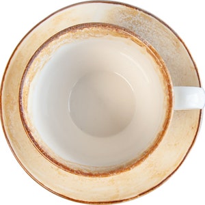May include: A white ceramic teacup with a brown rim and a matching saucer. The cup and saucer are empty.