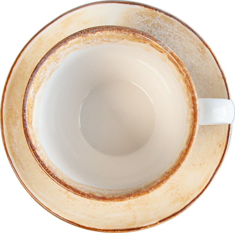 May include: A white ceramic teacup with a brown rim and a matching saucer. The cup and saucer are empty.